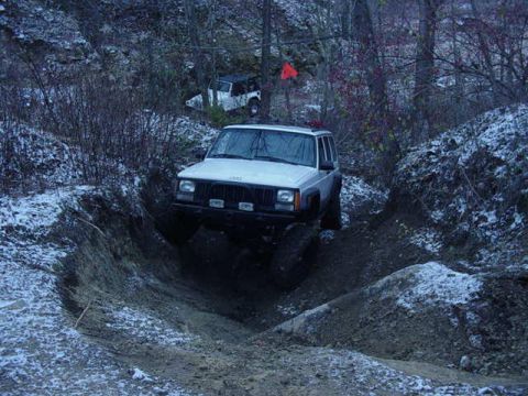 1992 Ford Bronco - A white Jeep Cherokee tackles a challenging off-road trail with another vehicle visible in the background.