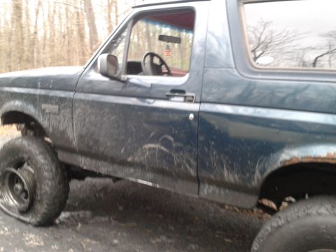 1995 Ford Bronco - This 1995 Ford Bronco is seen from the side, appearing muddy with a flat tire.