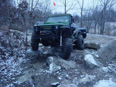 1992 Ford Bronco - Two off-road vehicles tackle a challenging rocky and muddy course in winter conditions.