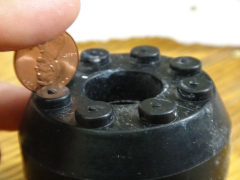 2000 Lincoln Continental - A penny is held next to a black plastic component with six protruding bolts, showing scale.
