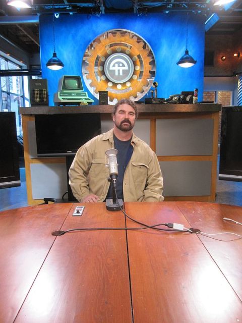 1990 Ford Bronco - A man sits at a table in a studio setting, with a microphone and vintage computer equipment visible.