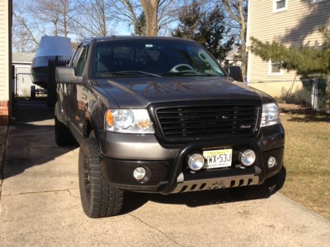 2008 Ford F-150 - This Ford F-150 is towing a boat on a trailer, parked in a driveway on a sunny day.