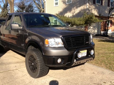 2008 Ford F-150 - This dark gray Ford F-150 truck is viewed from a 3/4 front angle, showing its black grille and bull bar.