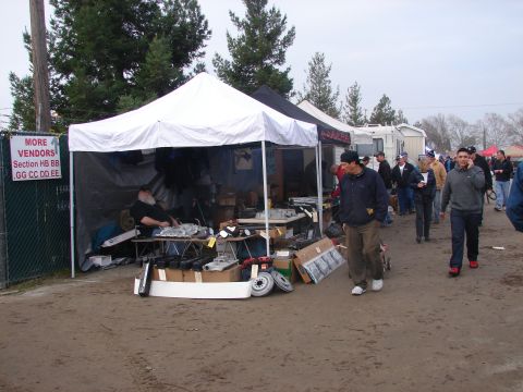 1973 Ford Ranchero - A busy outdoor swap meet with vendors displaying parts under tents and shoppers walking around.