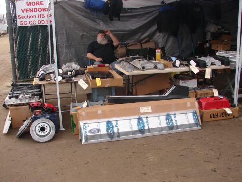 1973 Ford Ranchero - Swap meet vendor displays a variety of automotive parts, including engine components and boxed Ford service parts.
