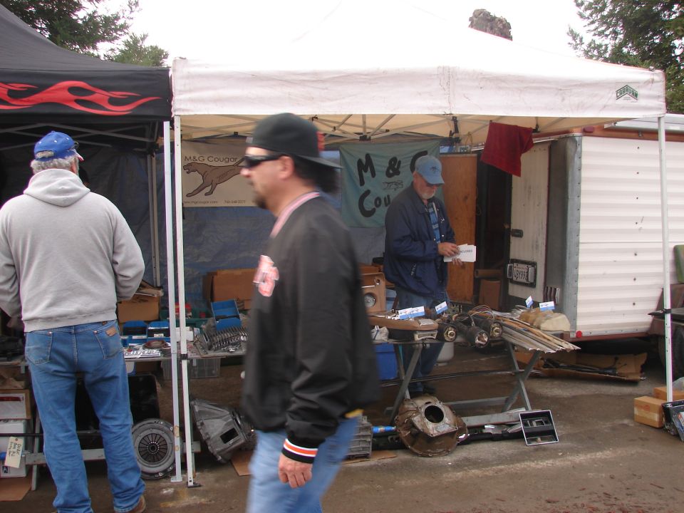 Outdoor market scene with various auto parts displayed under tents