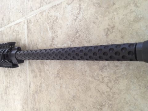 2013 Ford Mustang - A close-up, side view of a black, perforated rifle barrel with a rail system visible on the left. The barrel rests on a light-colored tiled…