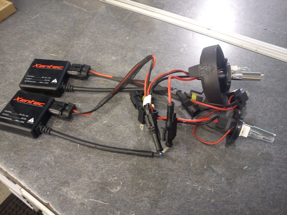 Xentec HID headlight kit with two ballasts, wiring, and bulbs on a gray workbench