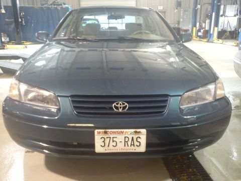 1998 Toyota Camry - Front view of a dark green 1998 Toyota Camry, identified by its grille and badge, parked indoors.