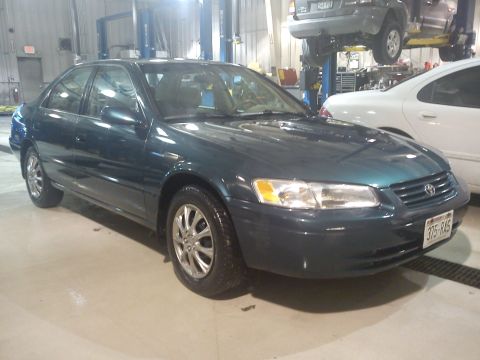 1998 Toyota Camry - This 1998 Toyota Camry is shown from the front three-quarter view in a garage setting, with another vehicle visible in the background.