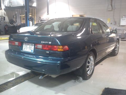 1998 Toyota Camry - Rear view of a dark green 1998 Toyota Camry sedan parked in a garage on a lift.