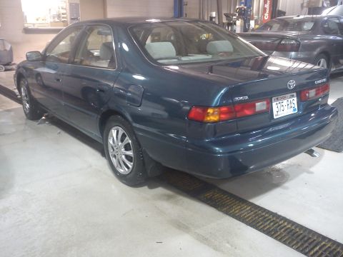 1998 Toyota Camry - A dark teal 1998 Toyota Camry sedan is shown from the rear three-quarter angle in what appears to be a service bay.