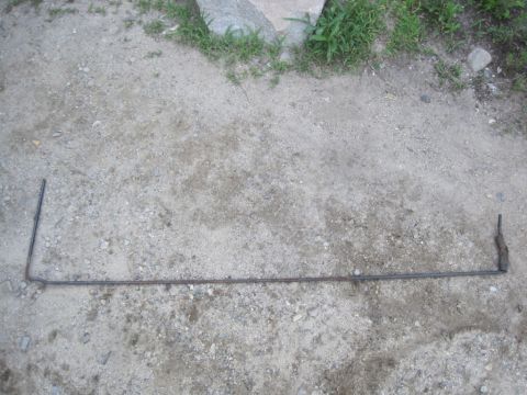 1993 Ford Bronco - Metal rod with bends, possibly a linkage or lever, shown on a dirt surface.