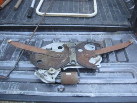 1993 Ford Bronco - This is a window regulator mechanism with a motor, likely for a vehicle door.