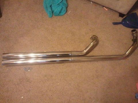 1995 Ford F-150 - Chrome exhaust pipes are laid out on a carpeted surface, with a blue funnel and teal cloth in the background.