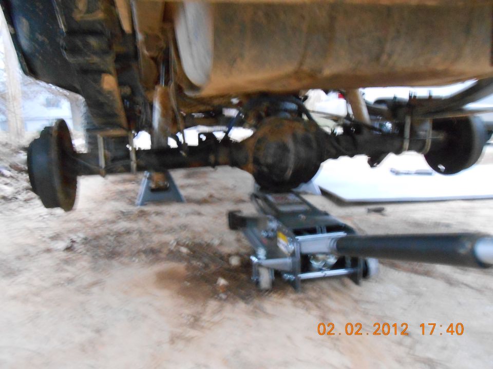 Vehicle rear axle assembly on jack stands with a floor jack underneath