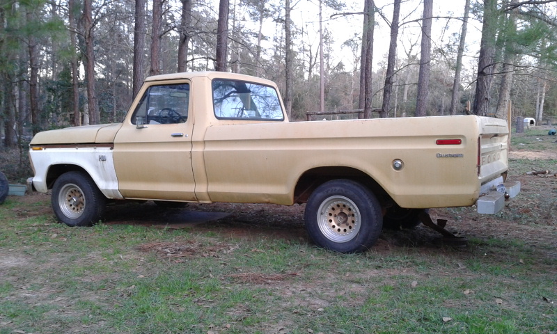 Faded tan Ford pickup truck side view parked in a wooded area