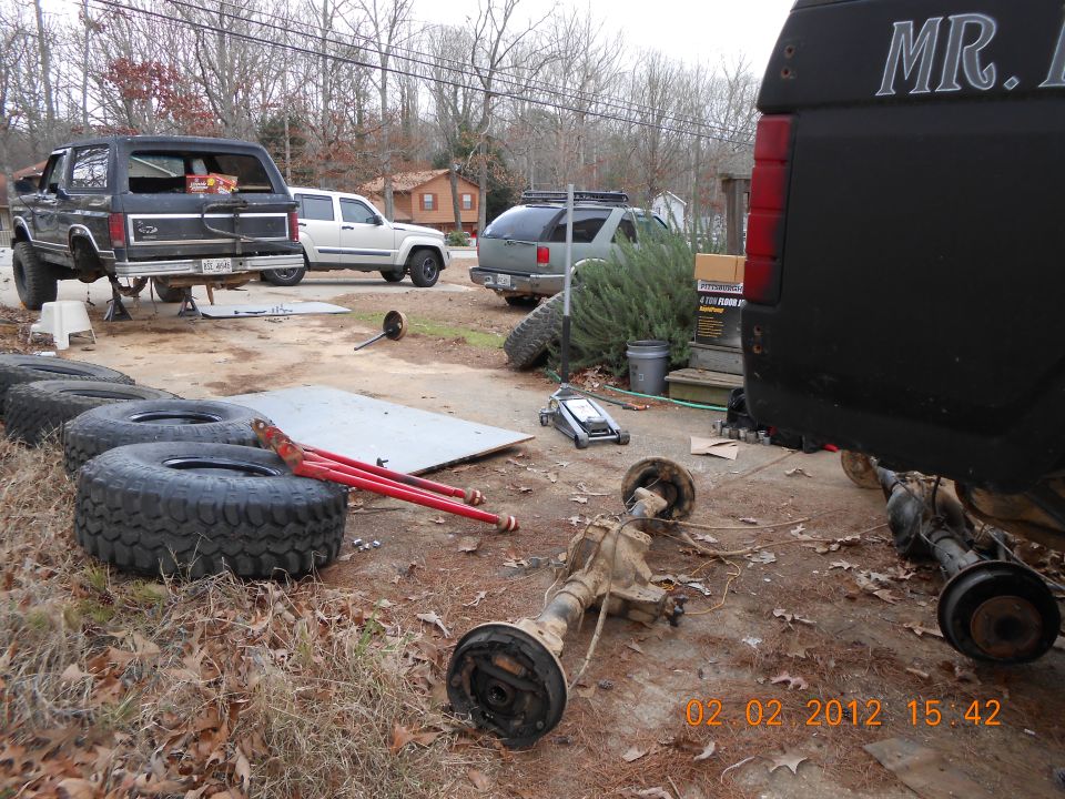 Black Ford Bronco and other vehicle parts in a driveway.