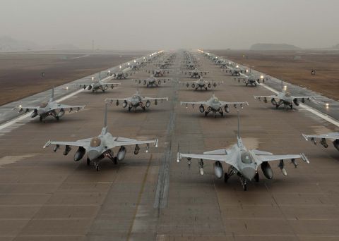 1989 Ford Bronco - Fighter jets are parked in formation on a runway under a hazy sky.