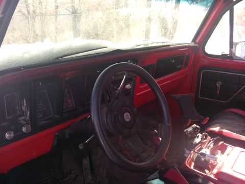 1979 Ford Bronco - The interior of a 1979 Ford Bronco shows a red dashboard and an aftermarket steering wheel, with snow visible on the exterior of the windsh…