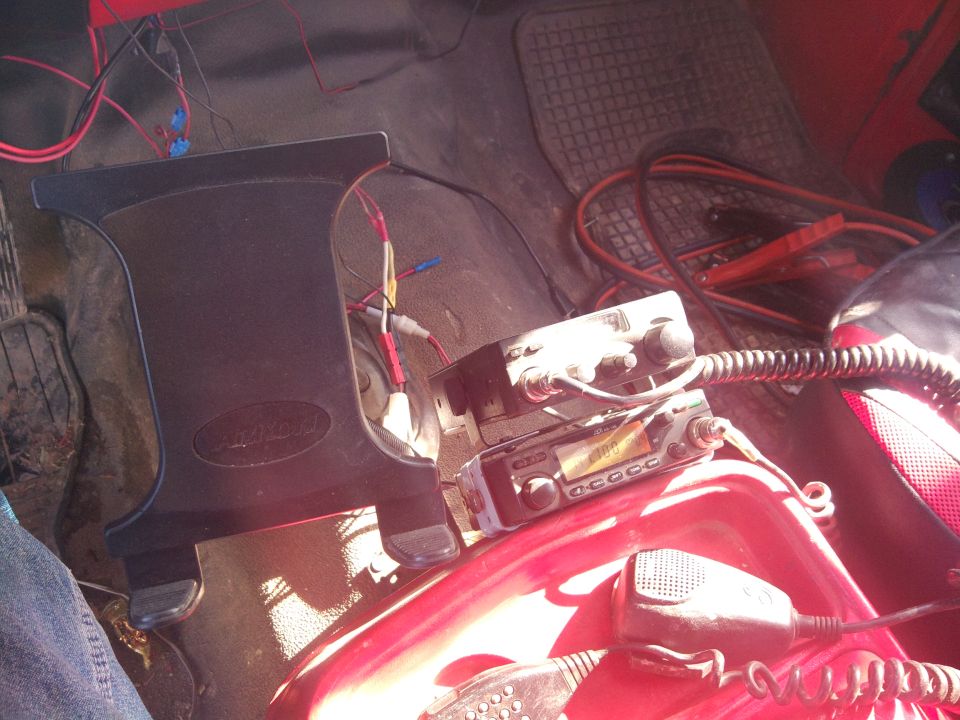 cb radios stacked on a red console with wires and jumper cables nearby