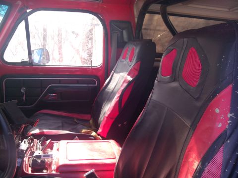 1979 Ford Bronco - The interior of this truck features custom seat covers with red accents and a roll cage visible.