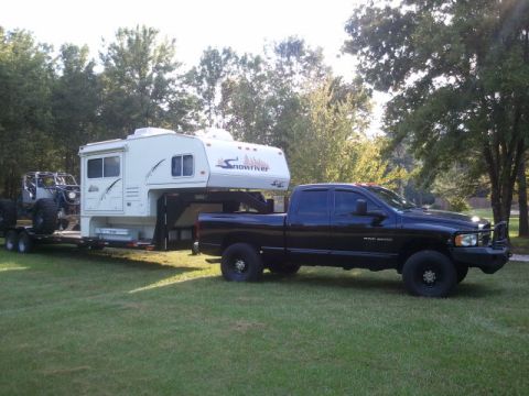 1967 Ford Mustang - A black pickup truck is shown towing a large camper and a jeep on a trailer.