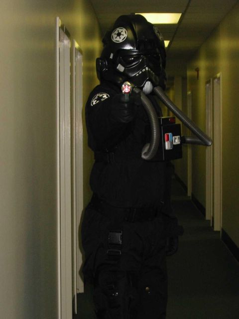 2000 Ford Taurus - A person dressed as a Star Wars TIE fighter pilot stands in a hallway, holding a prop.
