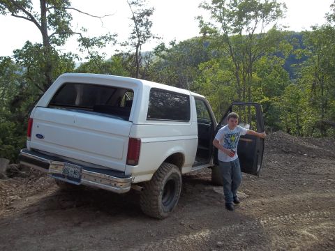 1990 Ford Bronco - White 1990 Ford Bronco parked off-road with a young man standing by the open door.