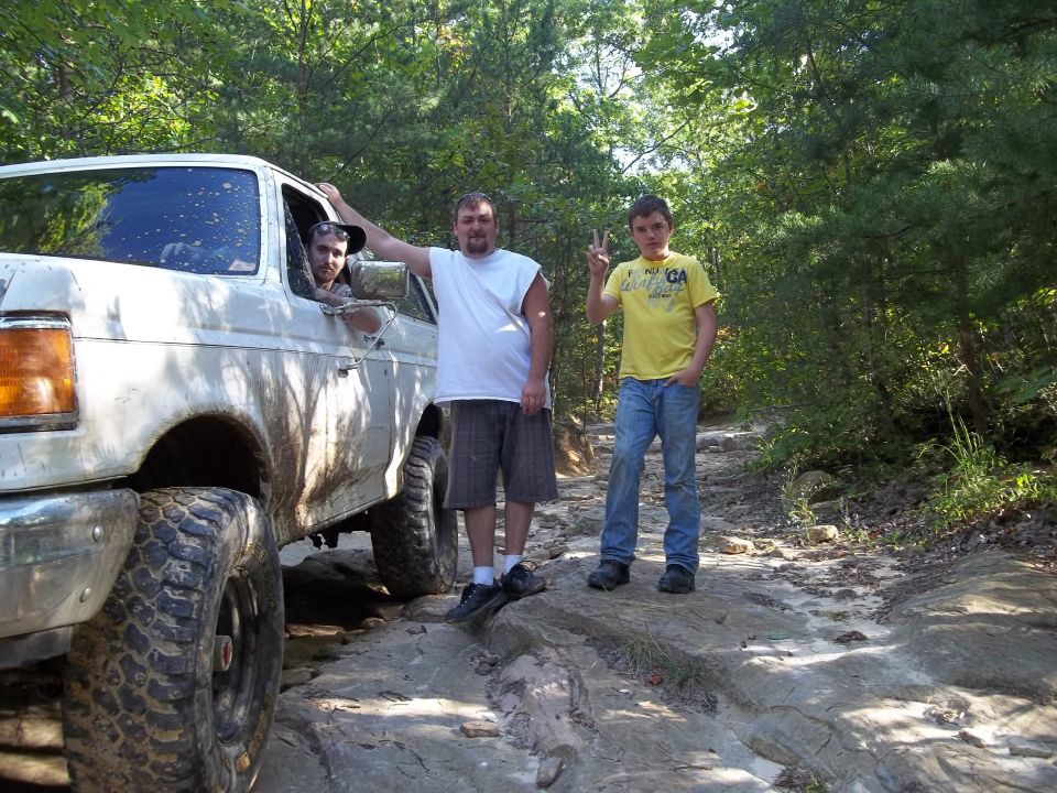 1990 Ford Bronco on a rocky trail with three people standing nearby