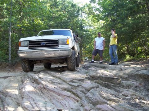 1990 Ford Bronco - A white Ford Bronco navigates a rocky off-road trail with two onlookers.