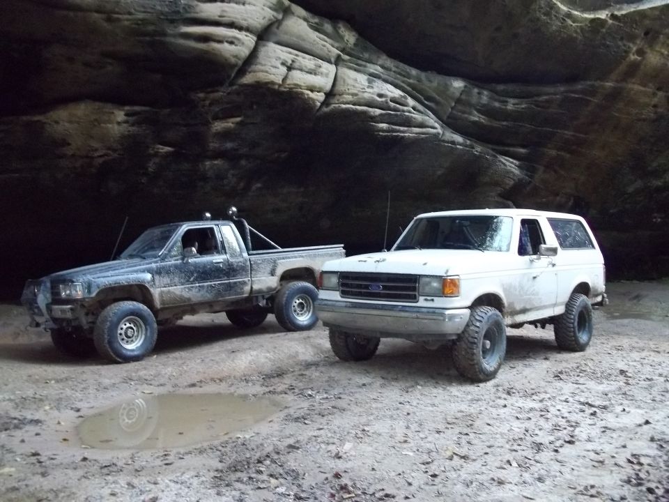 White Ford Bronco and black Toyota pickup truck parked in a rocky alcove