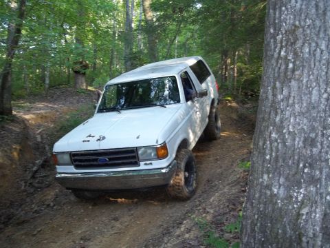 1990 Ford Bronco - This white Ford Bronco navigates a muddy forest trail.