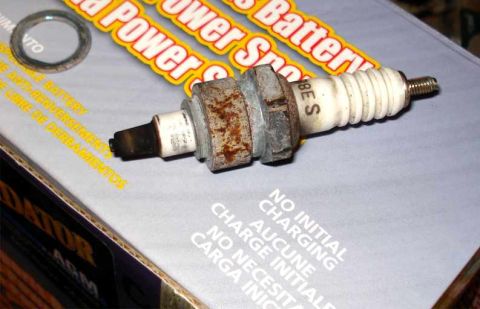 2008 Ford Crown Victoria - A used spark plug rests on a box that reads 'Power Spark Battery' and has multilingual instructions.