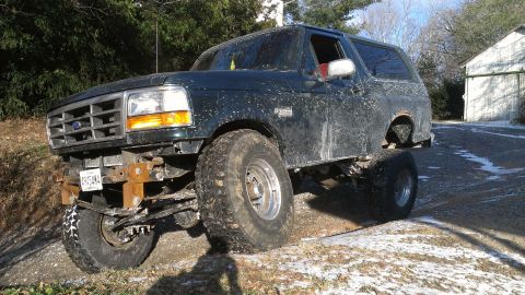 1995 Ford Bronco - This modified Ford Bronco is shown from a three-quarter front angle, appearing dirty and lifted.