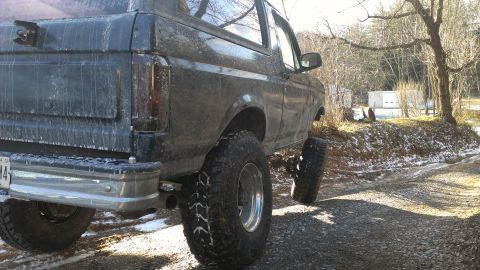 1995 Ford Bronco - Rear view of a lifted 1995 Ford Bronco on a snowy gravel road.