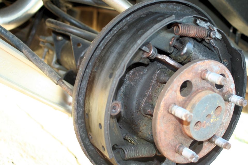 Close-up of a rusty rear drum brake assembly with brake shoes and springs visible