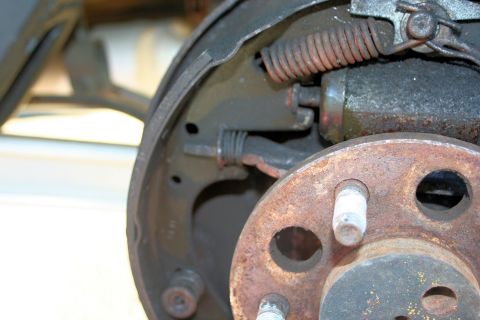 1976 Ford Ranchero - Close-up view of a rusty rear drum brake assembly, showing springs and wheel studs.