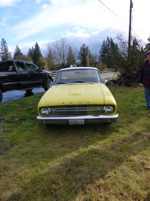 1961 Ford Ranchero - A yellow coupe utility, likely a 1960 model, is parked on grass with a black pickup truck nearby.