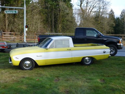 1961 Ford Ranchero - A two-tone yellow and white pickup truck is parked on grass next to a black pickup truck.