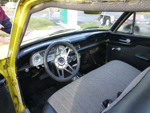 1961 Ford Ranchero - Interior of a classic car, likely from the early 1960s, with aftermarket steering wheel and custom seat upholstery.
