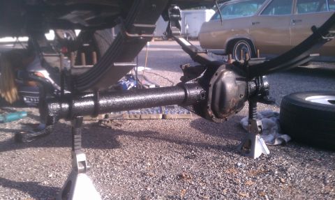 1995 Ford Bronco - The rear axle assembly is supported by jack stands, with a vintage car visible in the background.