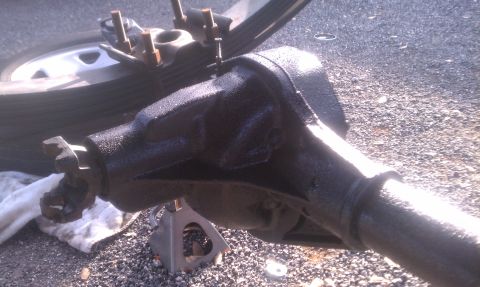 1995 Ford Bronco - Rear axle assembly, likely undergoing maintenance or repair, is supported by jack stands with a leaf spring and tire in the background.