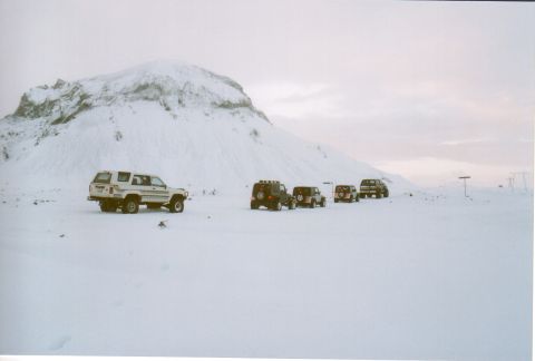 1996 Ford Bronco - A convoy of SUVs is parked in a vast, snow-covered terrain under an overcast sky.