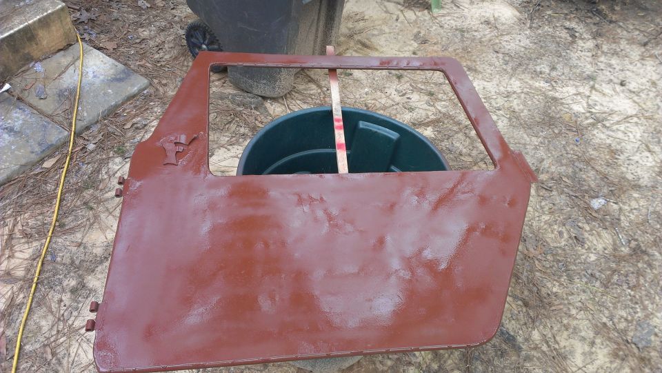 red vehicle door with a cutout for a window, resting on the ground