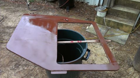1978 Ford Bronco - A car door, possibly undergoing restoration, is propped on a trash can outdoors.