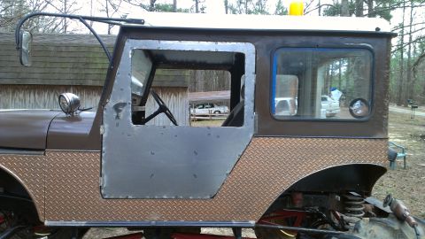 1978 Ford Bronco - Customized off-road vehicle cab with diamond plate accents and a metal door. Steering wheel is visible inside.