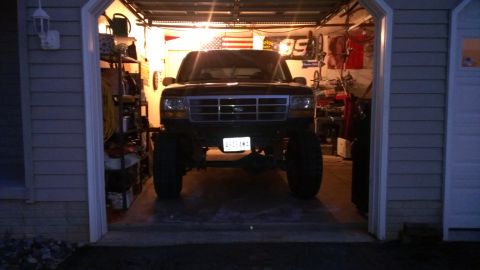 1995 Ford Bronco - This lifted 1995 Ford Bronco is parked head-on in a dimly lit garage.