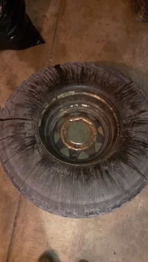 1995 Ford Bronco - A close-up view of a damaged tire and rim, likely in a garage or workshop setting.