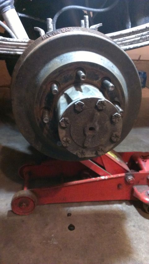1995 Ford Bronco - Close-up of a rear axle brake drum, showing the MAX. DIA. 1203 marking and resting on a red hydraulic jack.